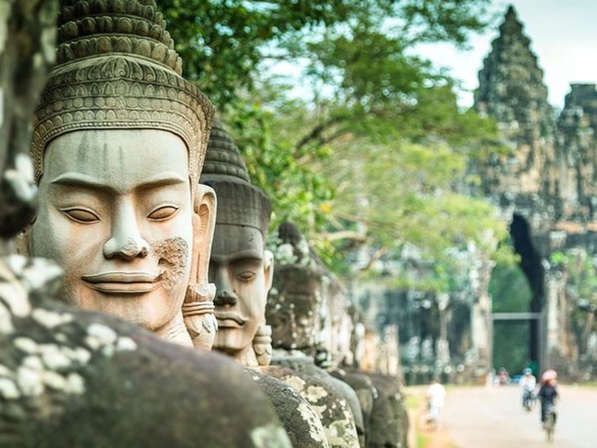 Stone statues at Angkor with temple background in Cambodia