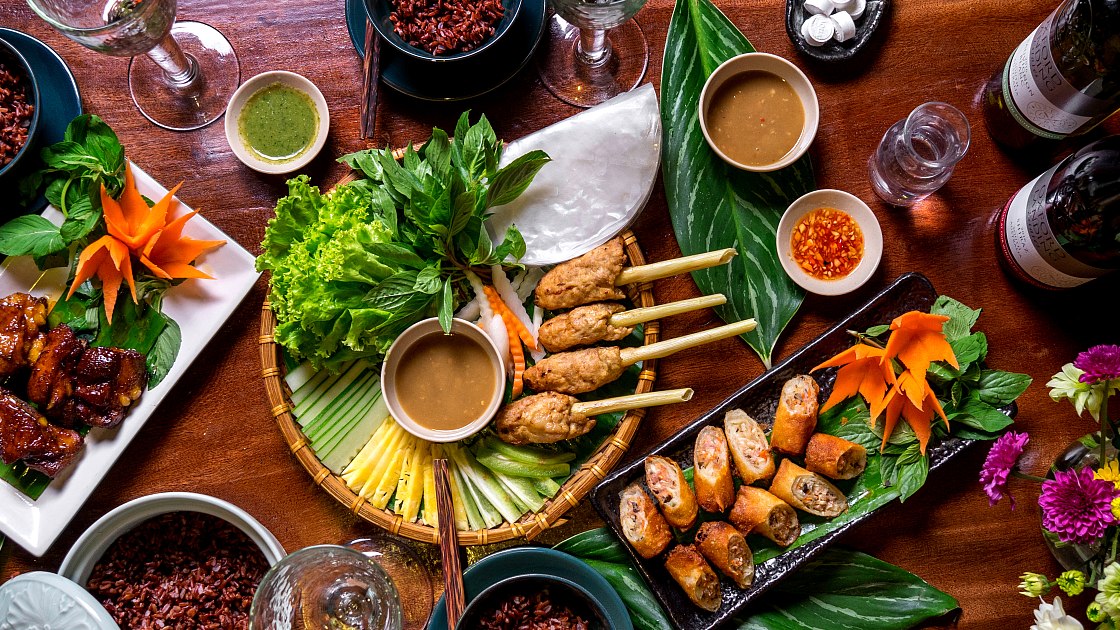 Vietnamese food spread with spring rolls, herbs, and grilled skewers