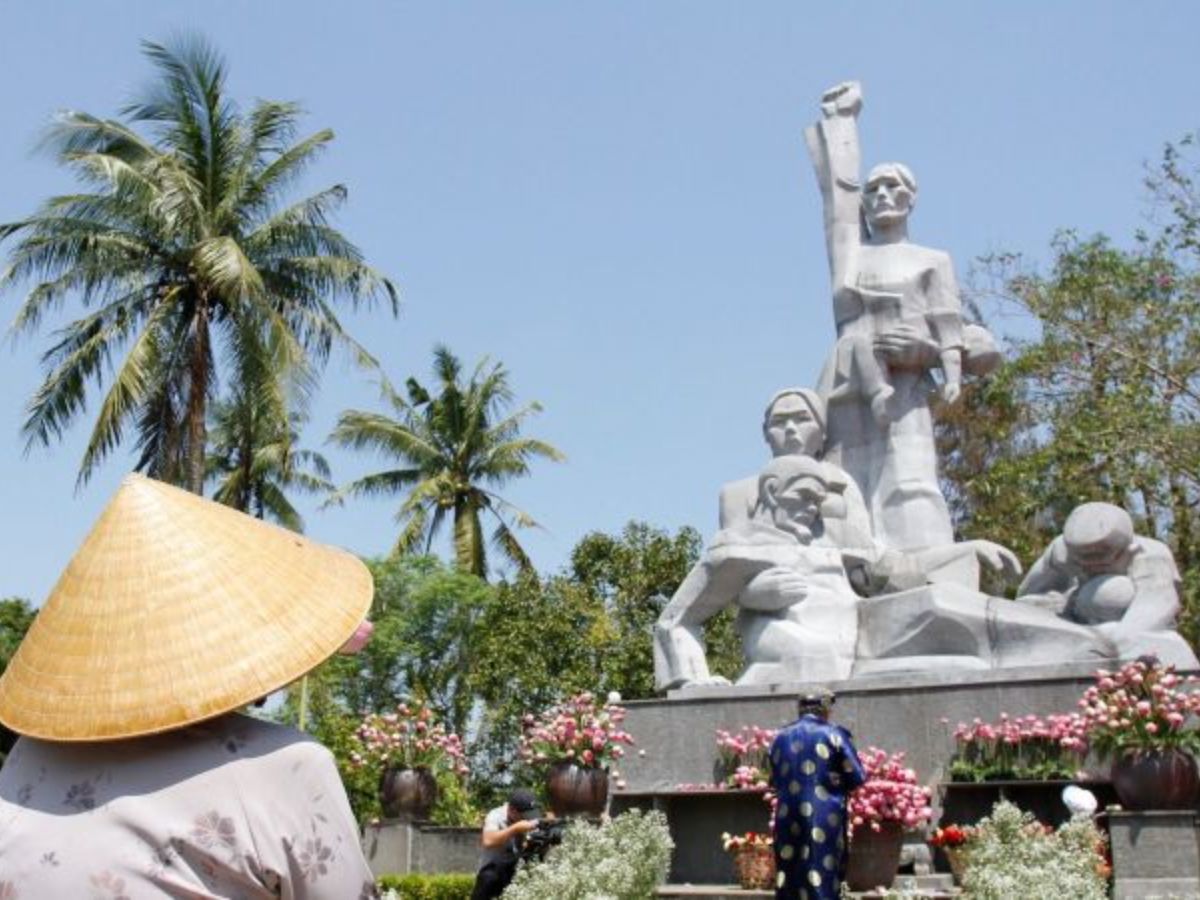 Vietnam War memorial with visitors and palm trees