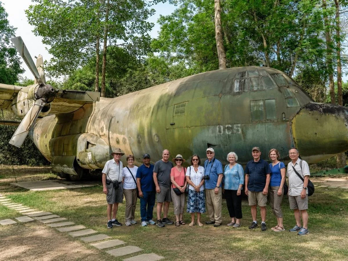 Adult travellers at a war-era aircraft display in Vietnam